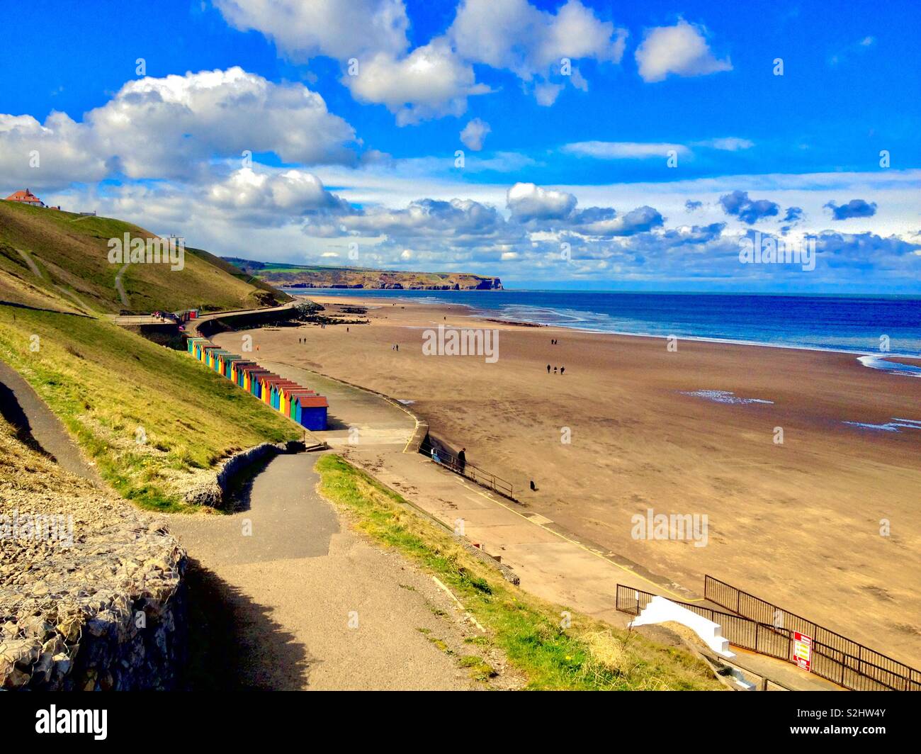 Colourful beach huts on a sandy beach with beautiful blue sea and skies Stock Photo