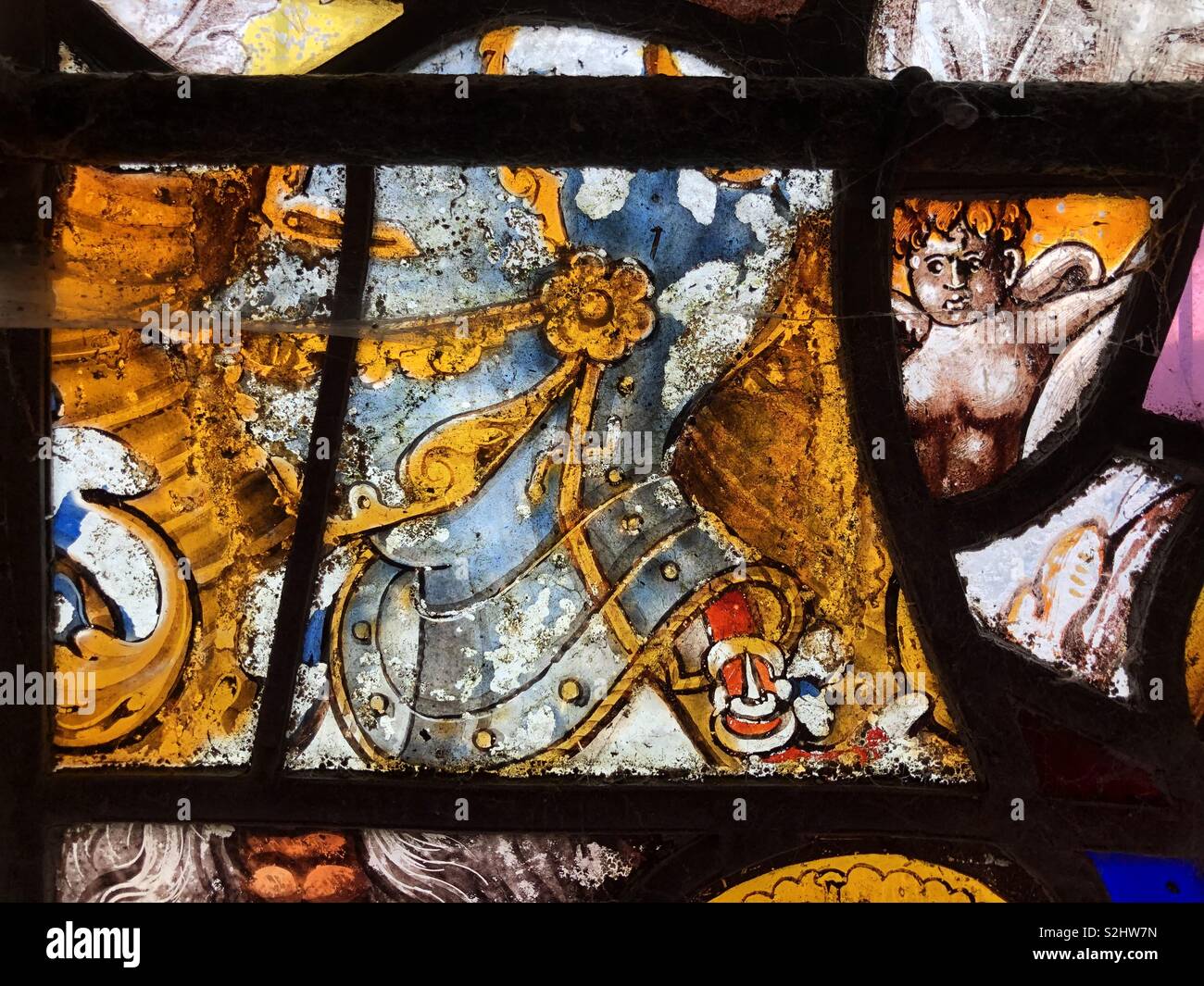 16th Century colourful stained glass depicting a knights helmet flanked by an unusual feminine cherub. - Smartphone Captured Stock Image