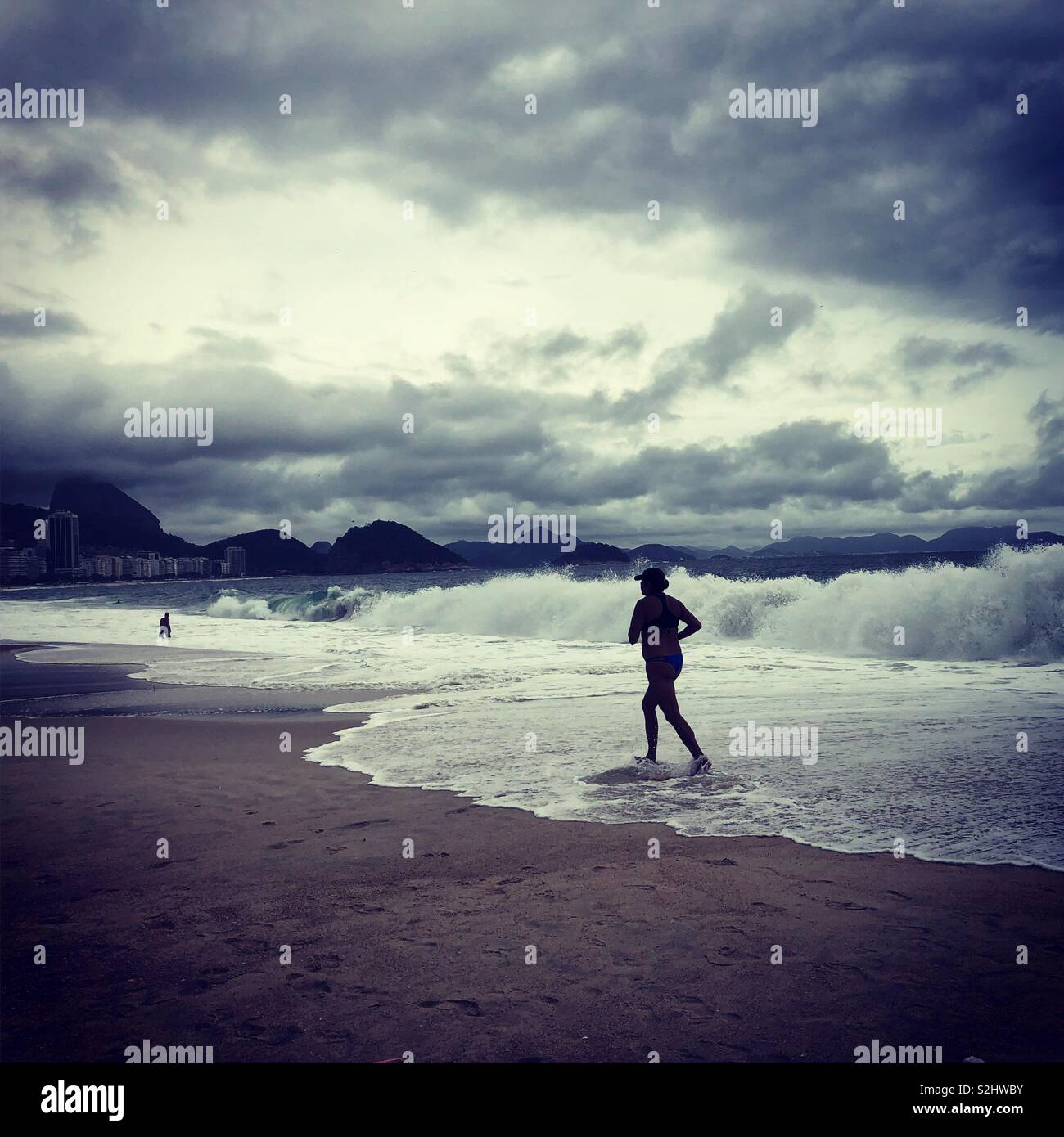 A female jogger on Copacabana beach in Rio de Janeiro, Brazil on a cloudy day. - Smartphone Captured Stock Image
