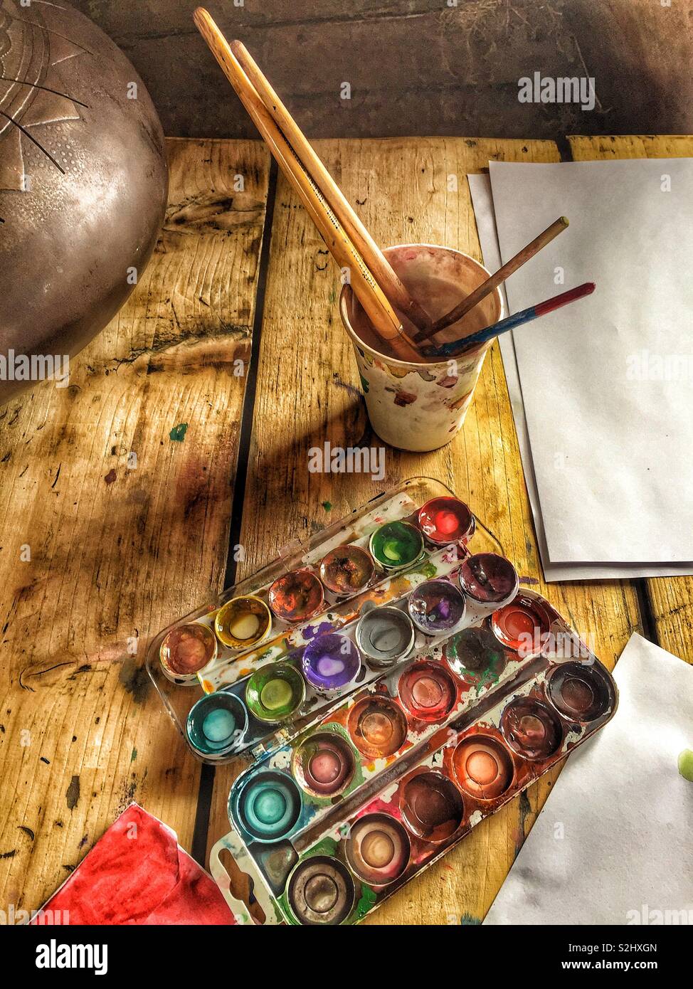 Painter’s working place, paints, brushes and paper on wooden table - Smartphone Captured Stock Image