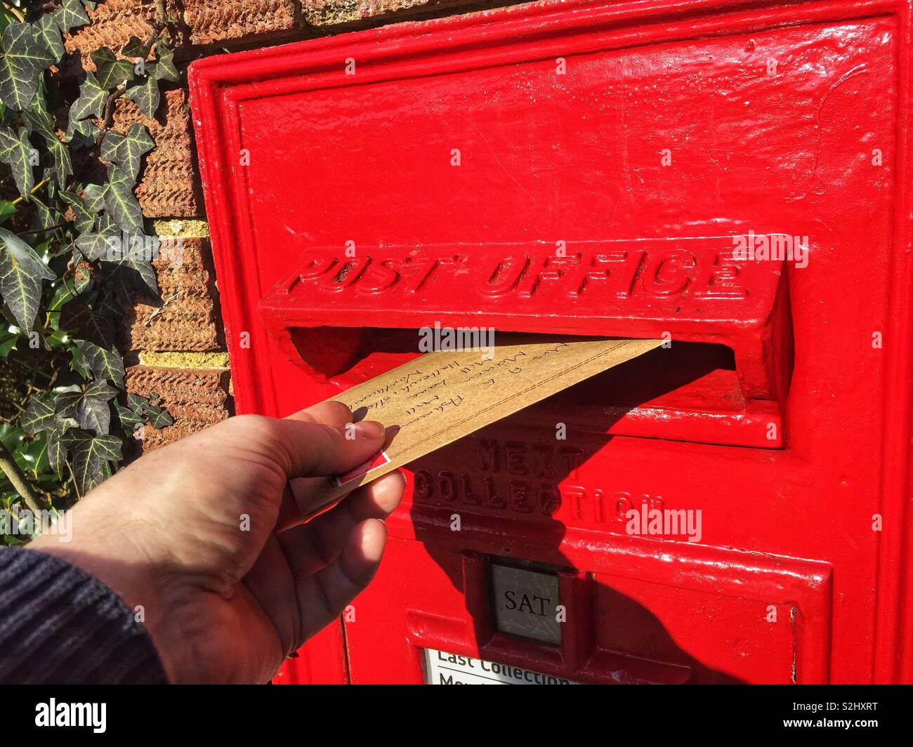 Hand posting a letter in a post box. - Smartphone Captured Stock Image