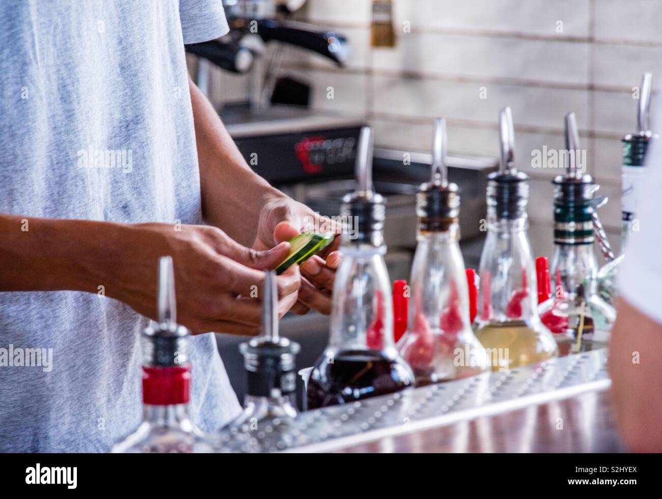 Bartender slicing cucumber for cocktails Stock Photo