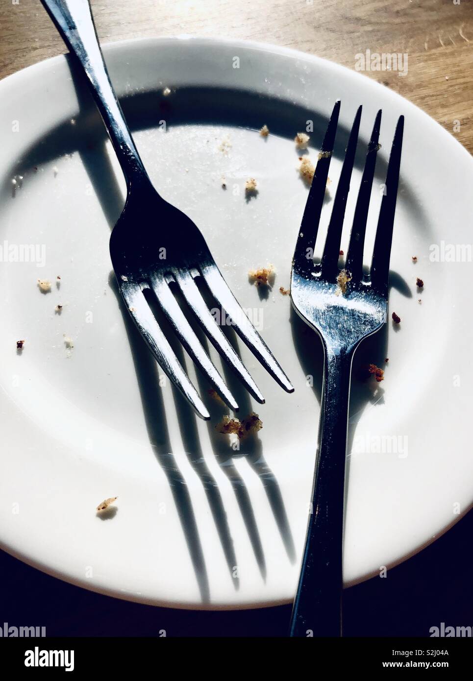 Two forks on a plate with crumbs Stock Photo