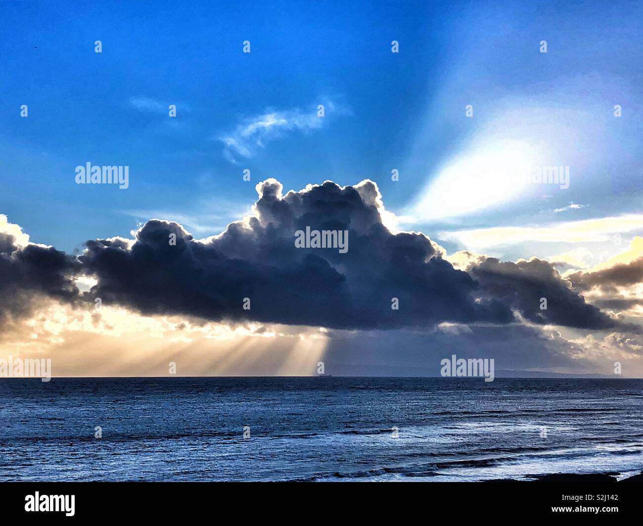 Sunburst from behind a dark cloud over the Bristol Channel, South Wales. - Smartphone Captured Stock Image