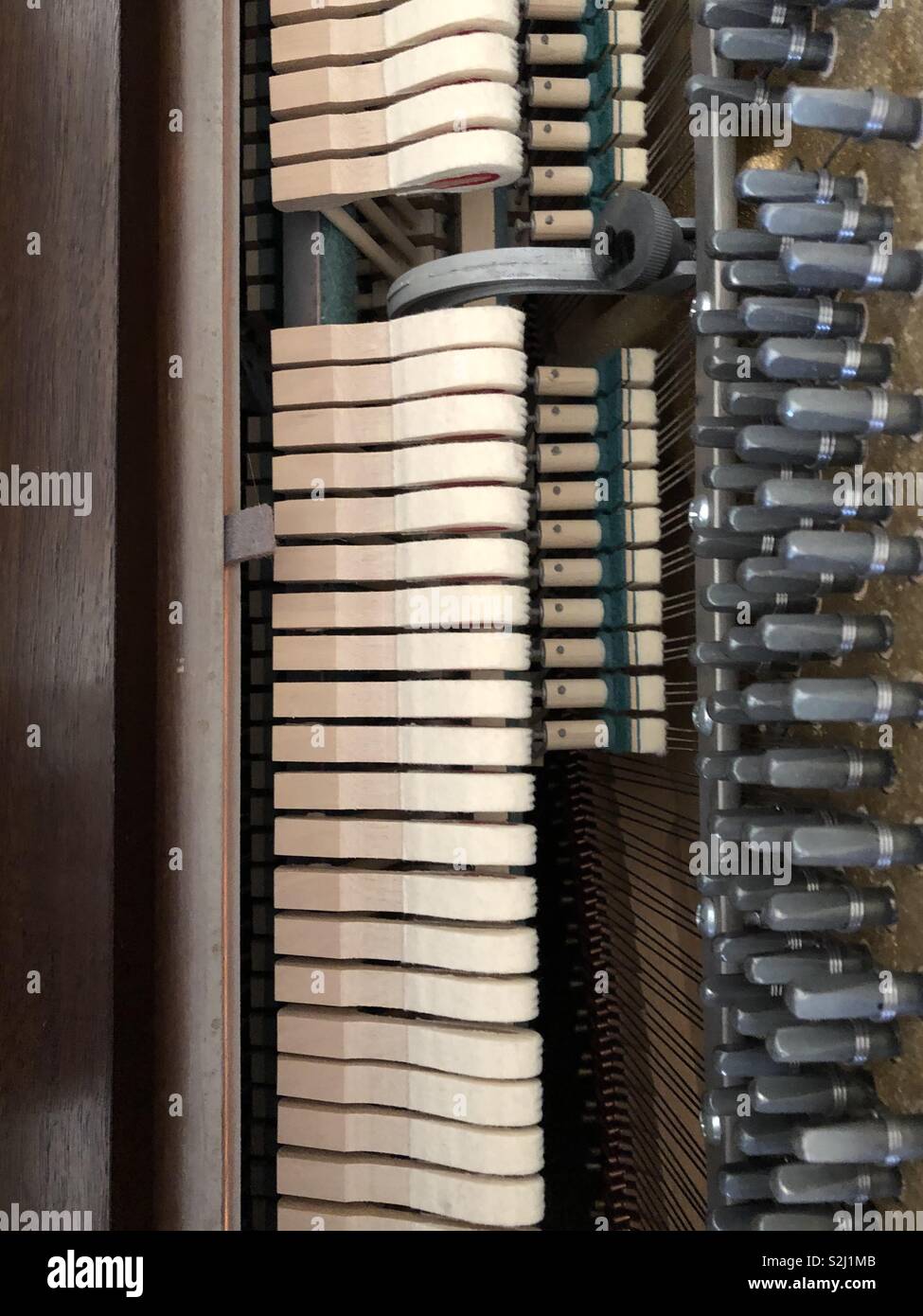 Piano hammers at the ready to hit the wires as the keys are played so as to make beautiful music. Stock Photo