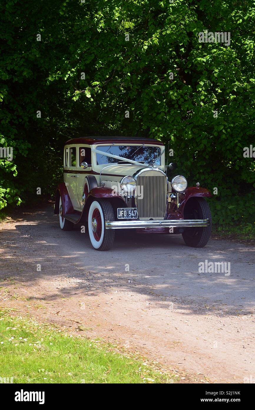A 1932 Buick Wedding Car emerging from a tree lined lane Stock Photo