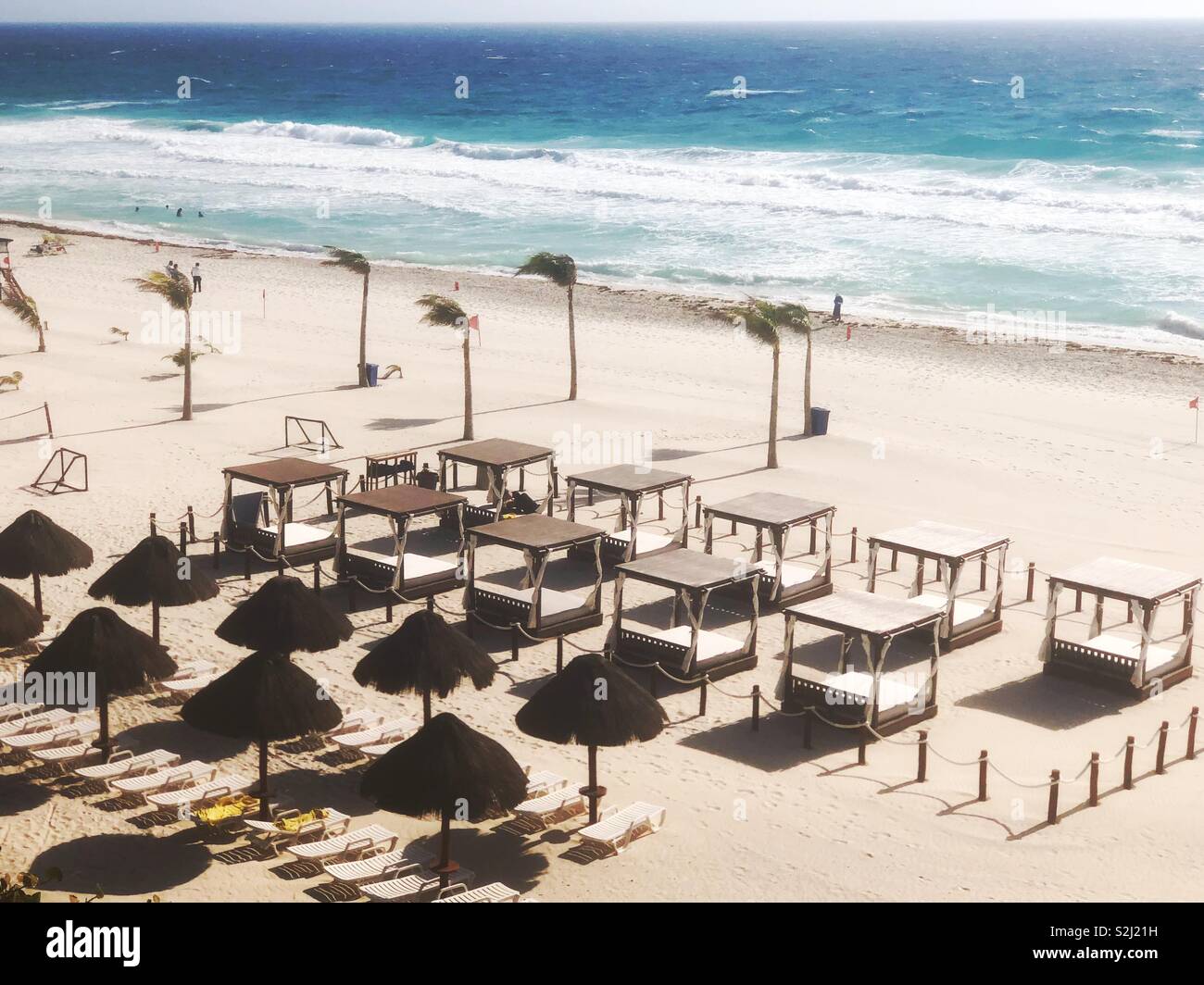Sunny empty beach with cabanas and umbrellas and palms in Cancun, Mexico - Smartphone Captured Stock Image