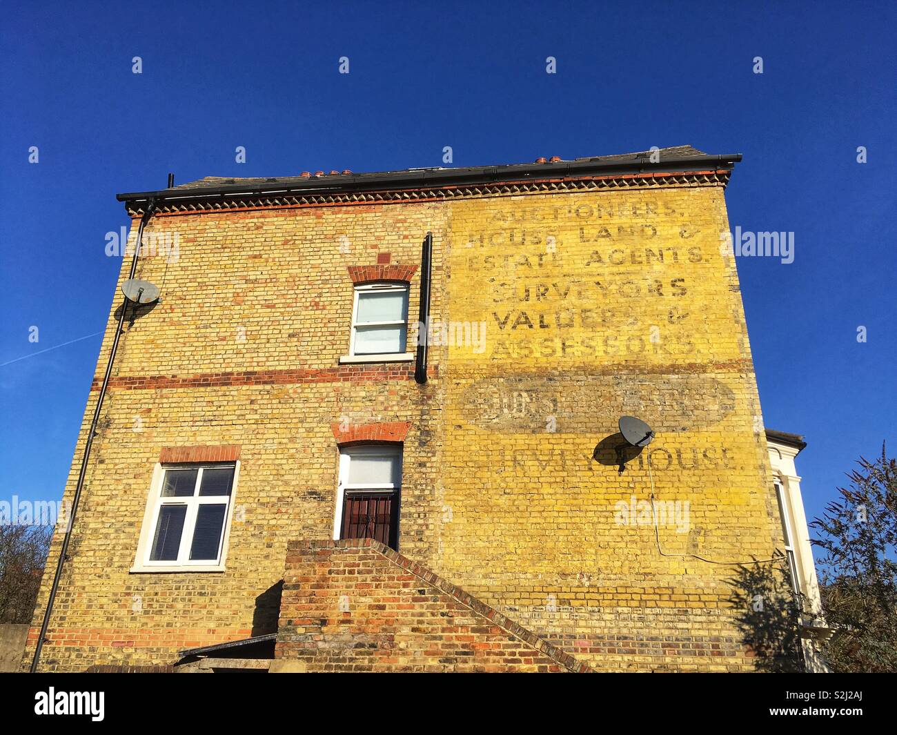 Old business advertising on a house on  Whatman Road Brockley Rise in London, England - Smartphone Captured Stock Image