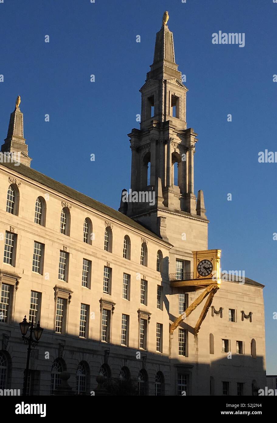 A side view of Leeds Civic Hall, in Millenium Square, West Yorkshire, England, in the evening sunshine. One of the front twin towers can be seen as well as one of the two gilded clocks at the sides. Stock Photo