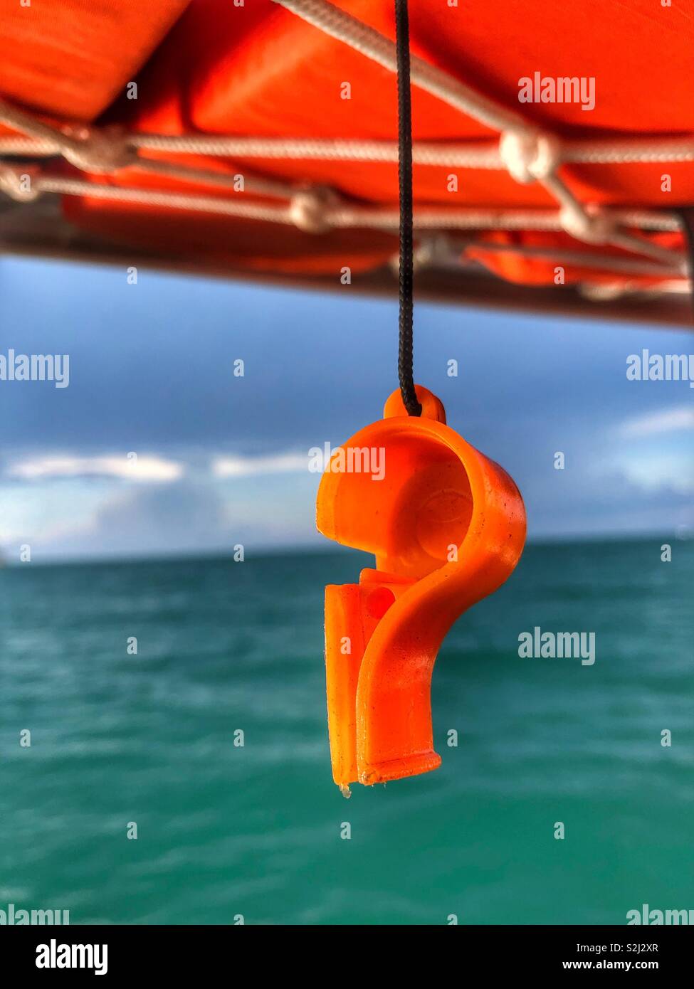 An orange whistle hanging from a life vest on a boat. - Smartphone Captured Stock Image