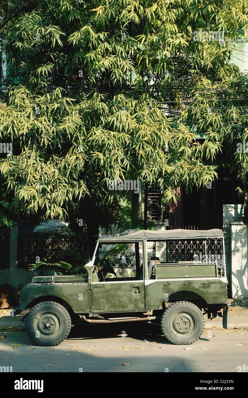 Old army land rover jeep, car under a tree Stock Photo