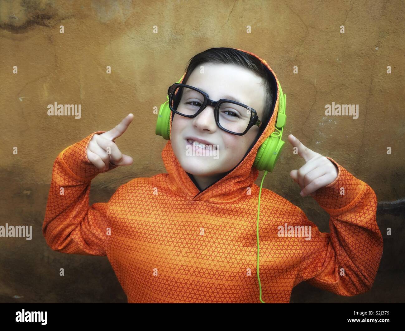 Young and happy boy with black glasses listening to music on stereo headphones Stock Photo
