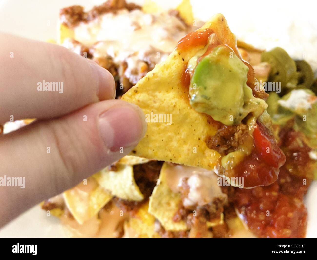 Male dings holding a nacho with salsa and guacamole. - Smartphone Captured Stock Image Male dings holding a nacho with salsa and guacamole. - Smartphone Captured Stock Image