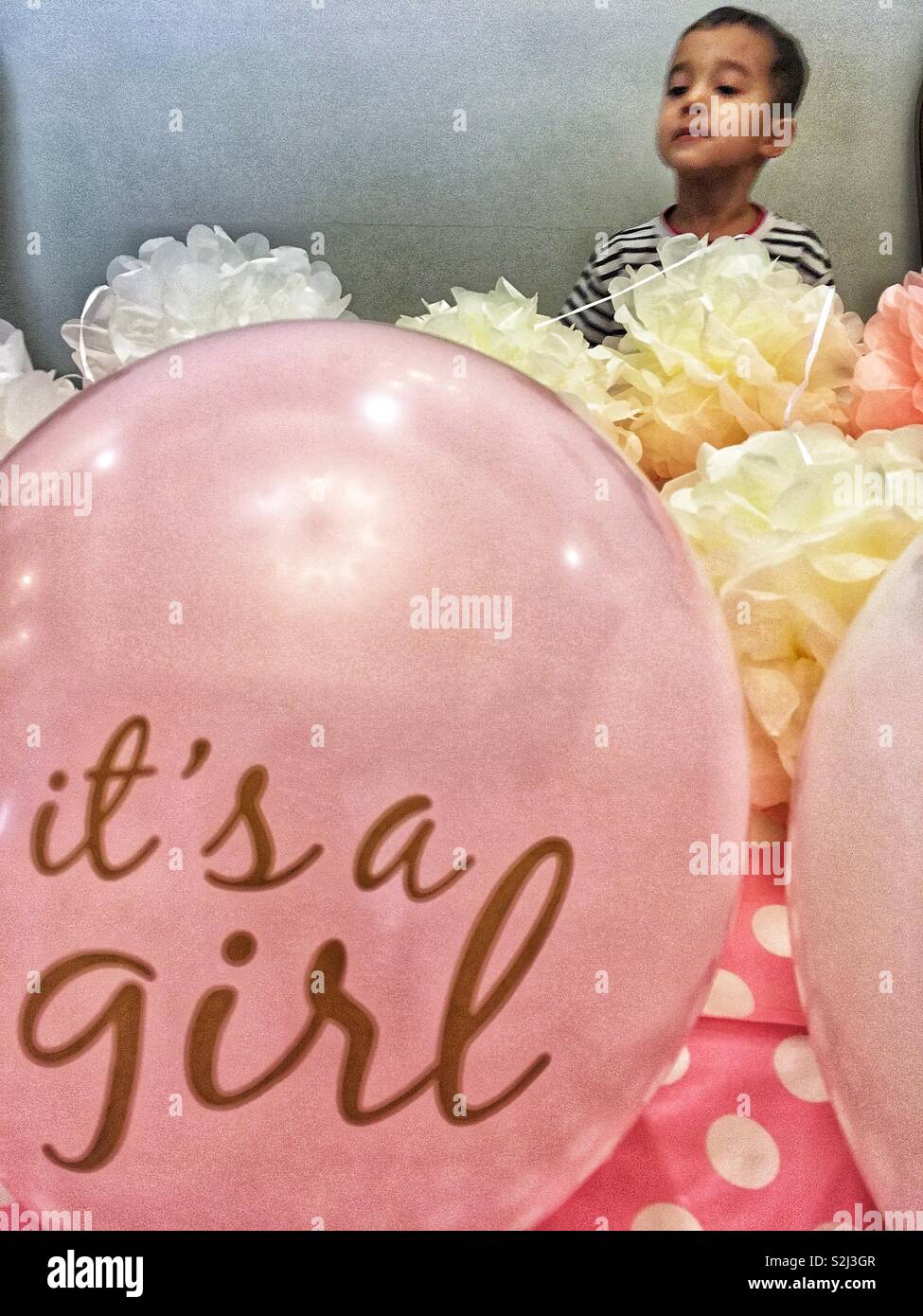 Gender conditioning. Pink girly decoration for baby shower and a toddler boy stick aside. - Smartphone Captured Stock Image