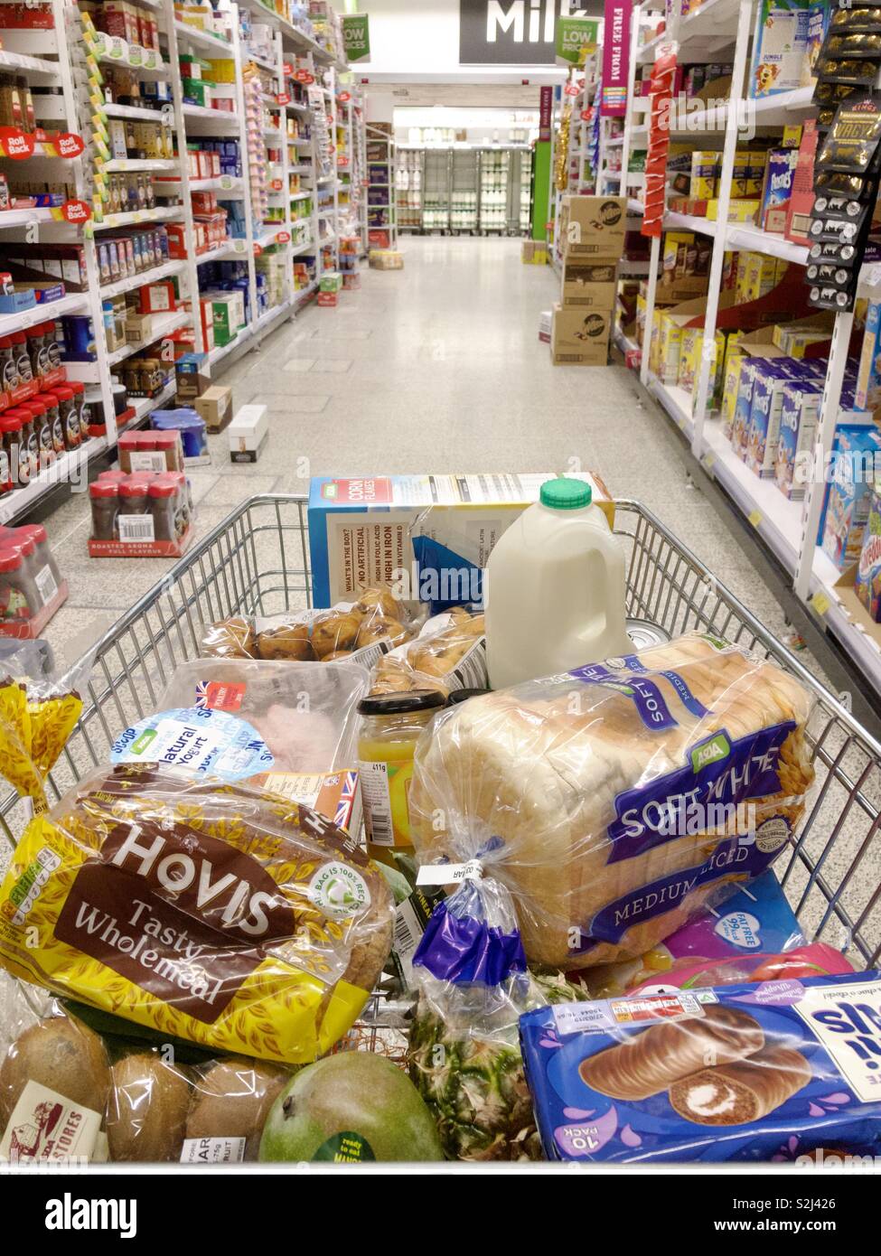 Trolley full of groceries in the middle of an aisle in a supermarket. - Smartphone Captured Stock Image