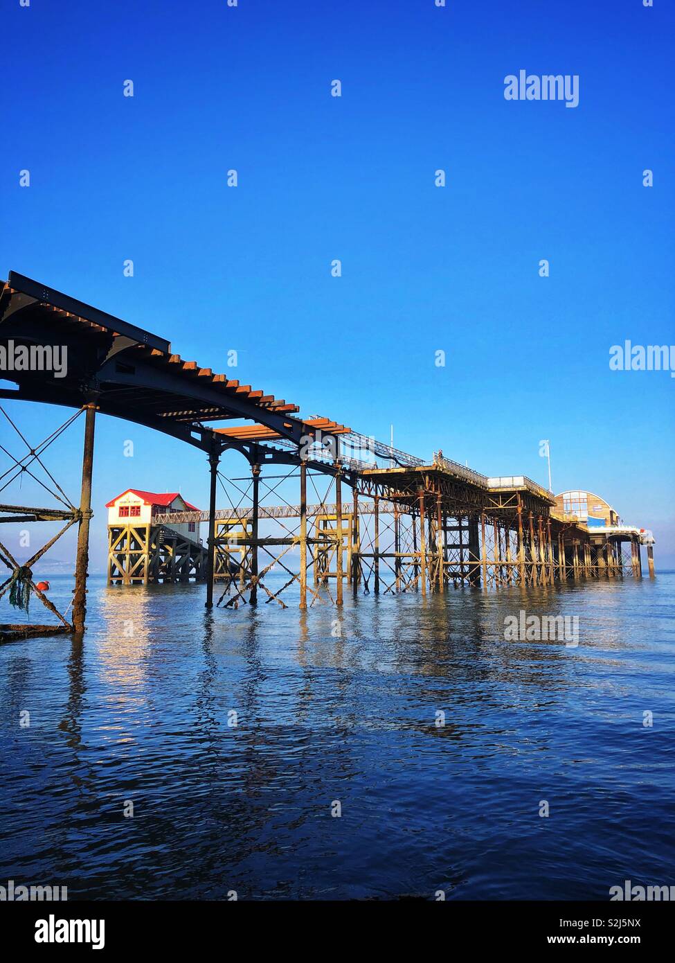 Old Mumbles lifeboat station framed by Mumbles pier with the new lifeboat station at the end, Swansea, South West Wales. - Smartphone Captured Stock Image