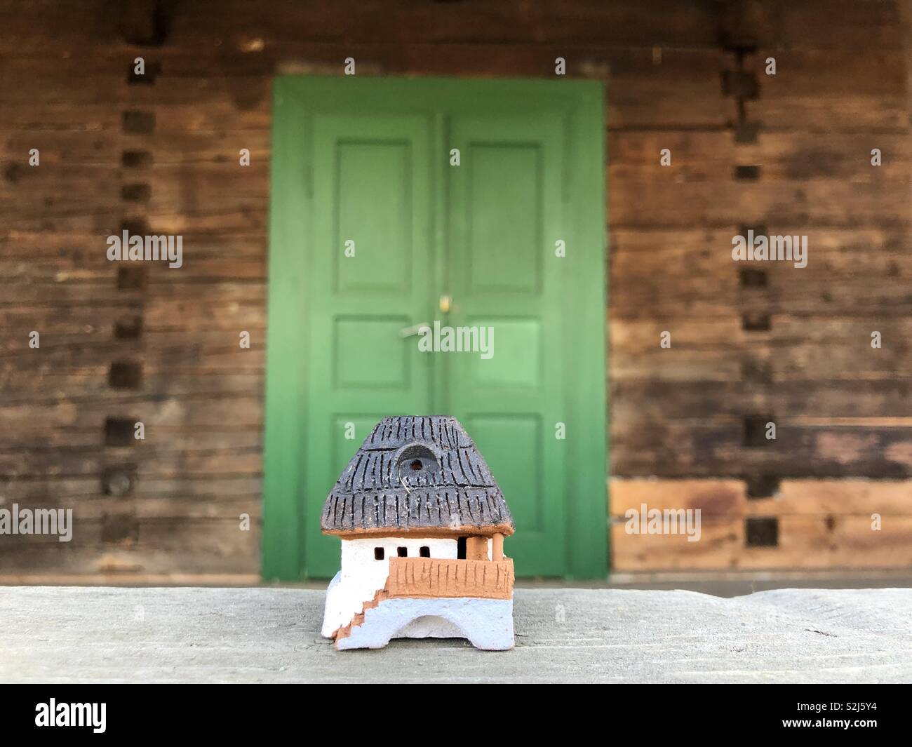 Terracotta traditional house miniature from Romania front of a green door - Smartphone Captured Stock Image