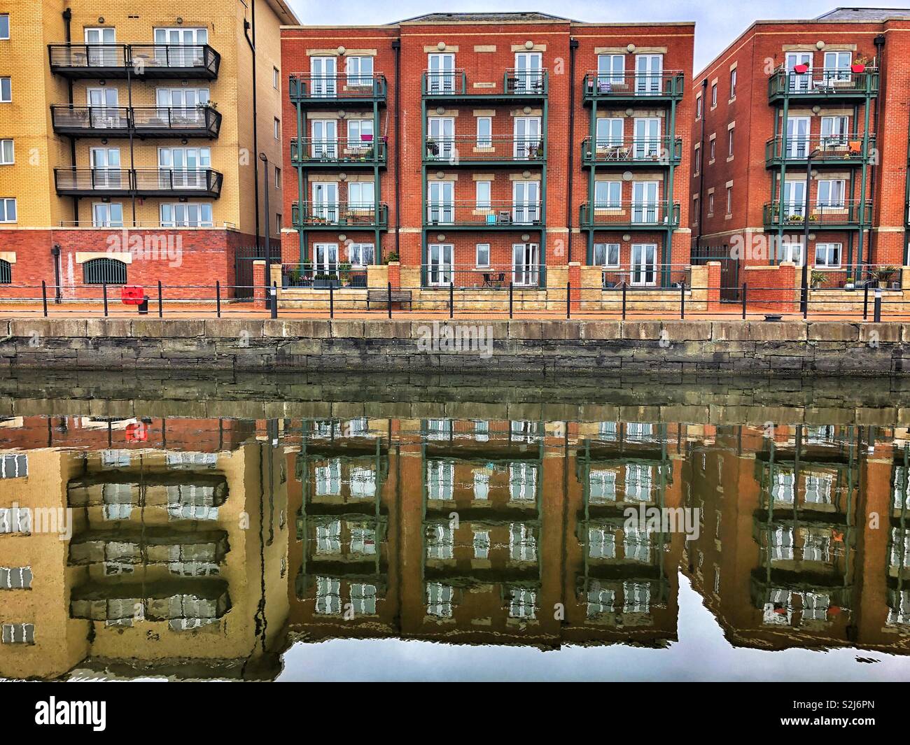 Waterside apartments reflected in the dock at Cardiff Bay, South Wales. - Smartphone Captured Stock Image