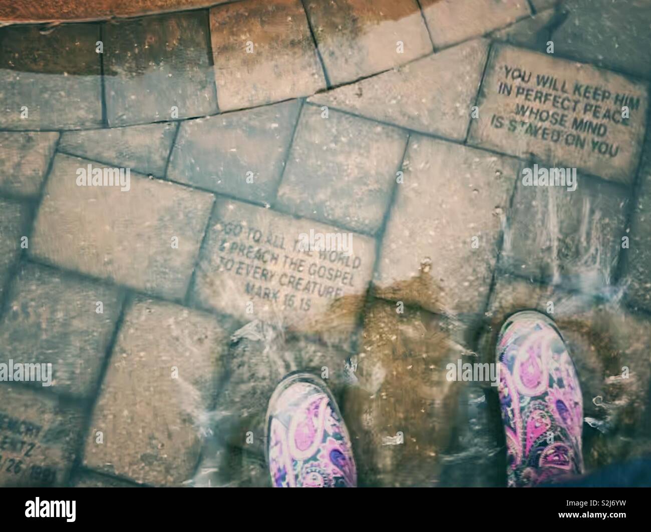 Bright paisley rain boots in flooded patio by fountain base make a splash - Smartphone Captured Stock Image