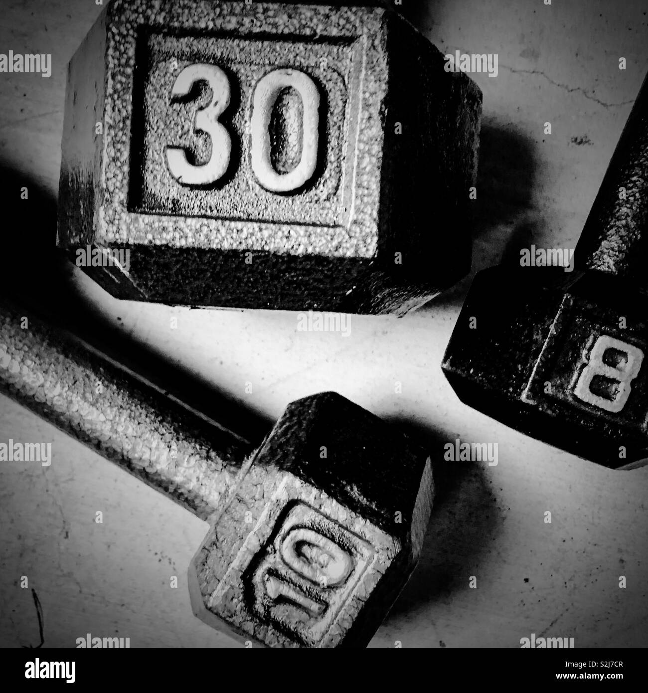 Assorted dumbbells on concrete floor in black and white - Smartphone Captured Stock Image