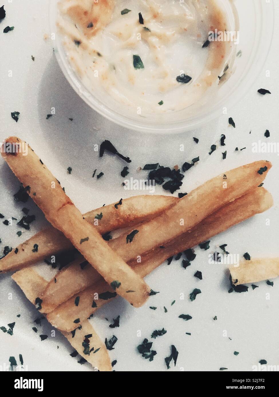 Close up of Japanese French fries sprinkled with sea weed with Mentai Mayo in a plastic cup on a styrofoam takeout box Stock Photo