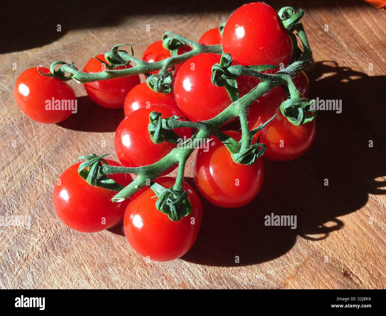 Tomatoes on the vine on chopping board Stock Photo - Alamy