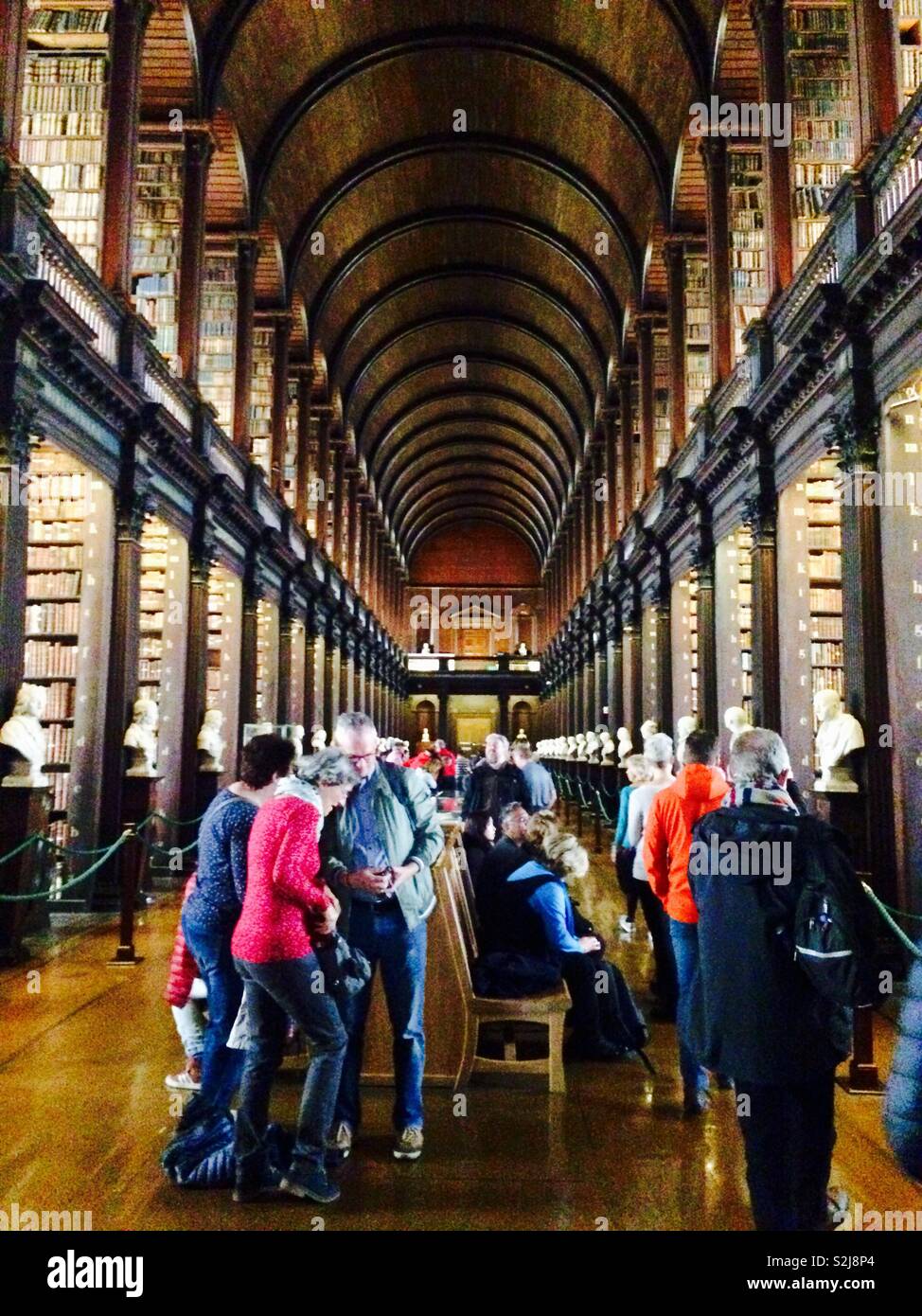 The Long Room of the Old Library at Trinity College in Dublin Ireland with many tourists and people visiting Stock Photo