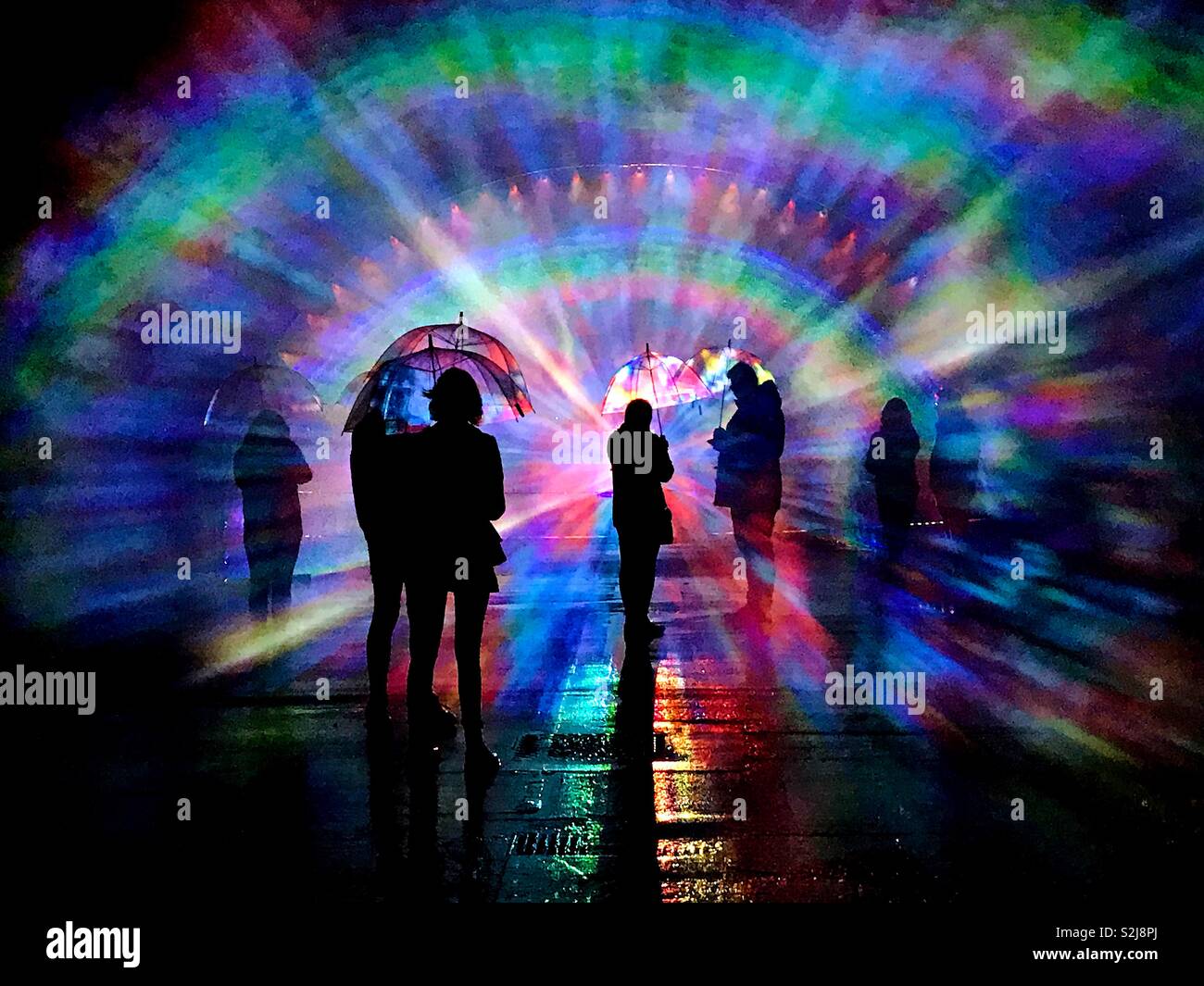 Plymouth Illuminate Light Festival where spectators can be part of the display shielded with umbrellas from water spray as they are silhouetted. Stock Photo