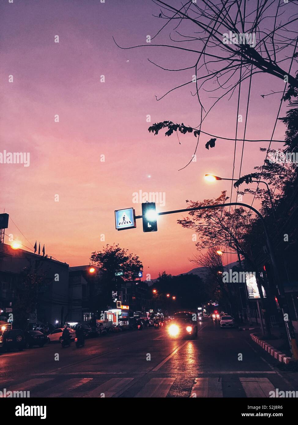 An peaceful evening in Chiang Mai, Thailand. This was taken on my way to visit old city. Love the color mixture of purple and orange of the sky and the traffic lighting. Stock Photo