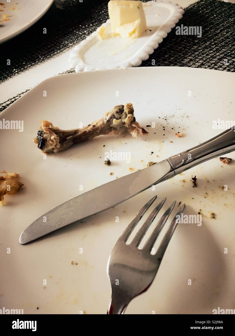 A single chicken bone and silverware at the completion of a meal, USA - Smartphone Captured Stock Image