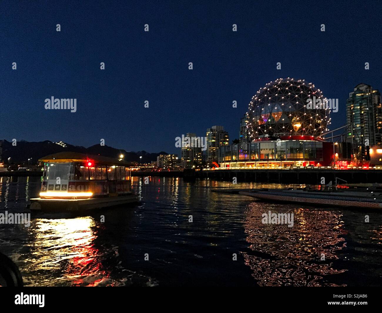 Passenger ferry approaches Telus World of Science in Vancouver Canada at night. - Smartphone Captured Stock Image