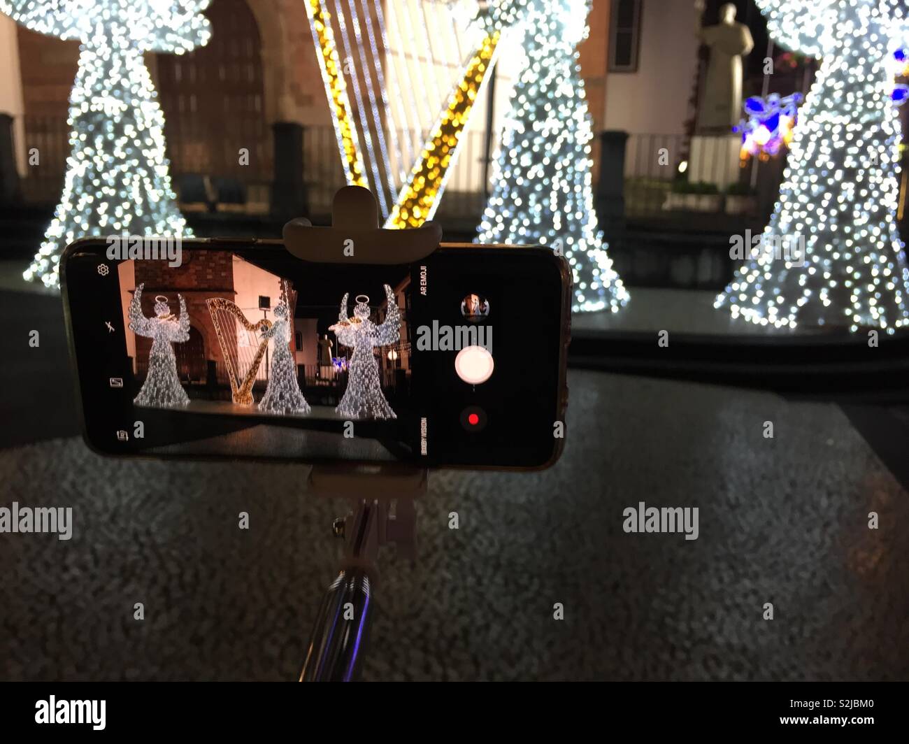 Using a mobile phone to photograph a Christmas lighting display of three angels. Stock Photo