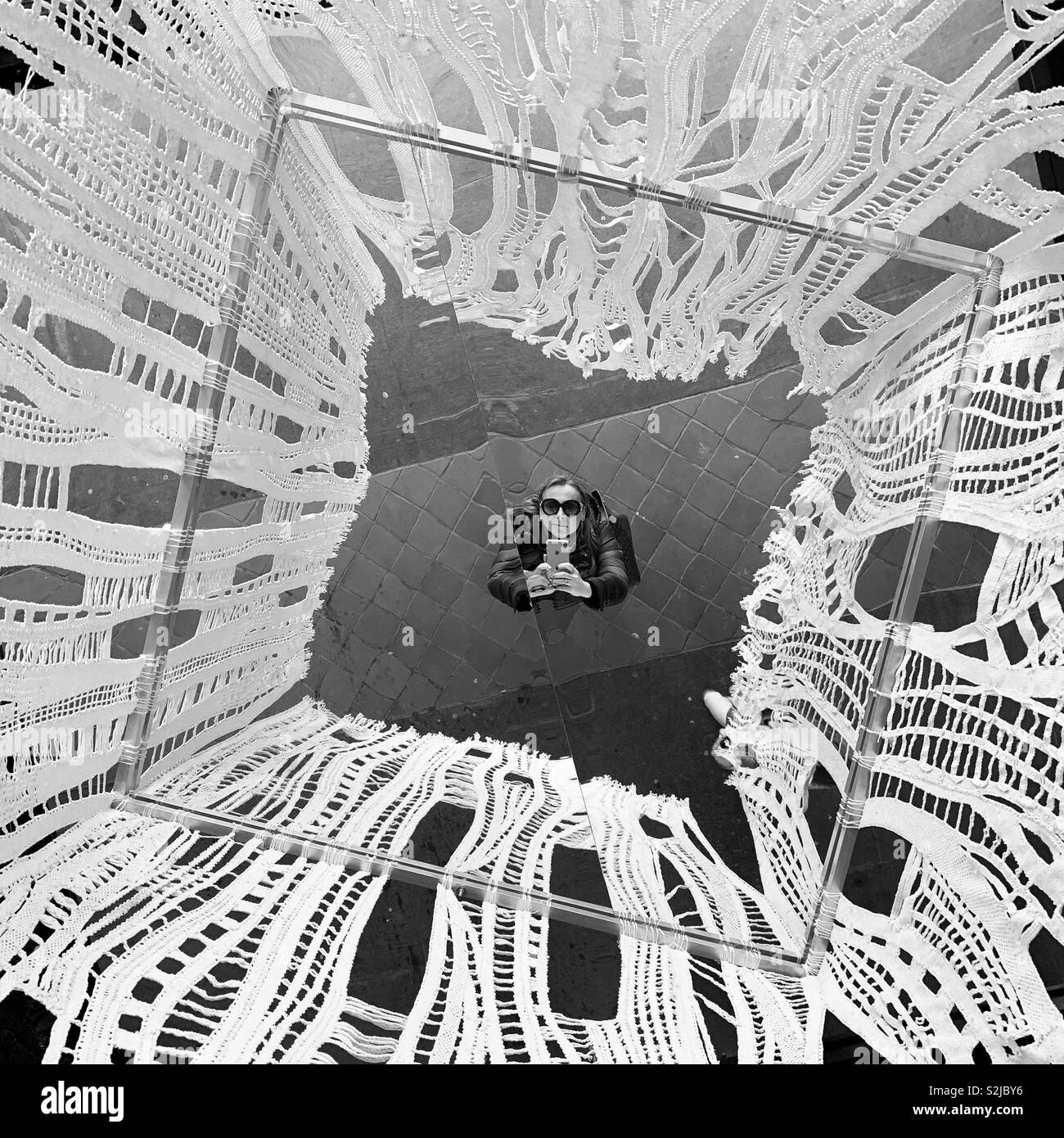 Woman taking a selfie in a mirror on a ceiling, framed in lace. Idrija, Slovenia. - Smartphone Captured Stock Image