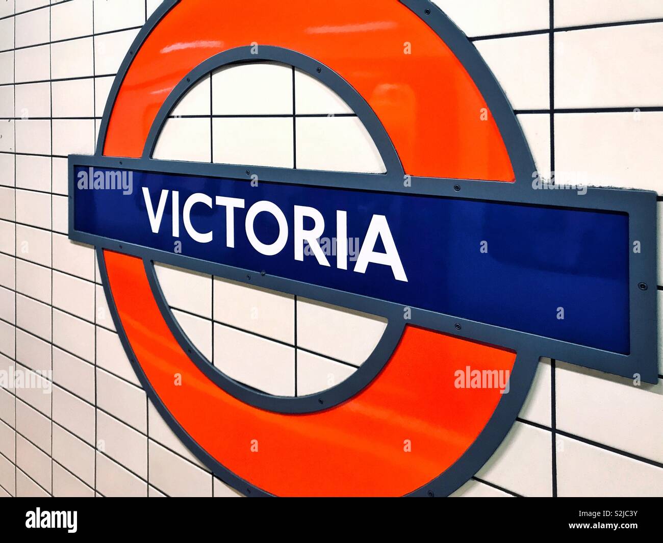 A London Underground sign indicating this station is VICTORIA. The iconic red circle and blue oblong, containing text easily identifies the London Underground system. Photo Credit - © COLIN HOSKINS. - Smartphone Captured Stock Image