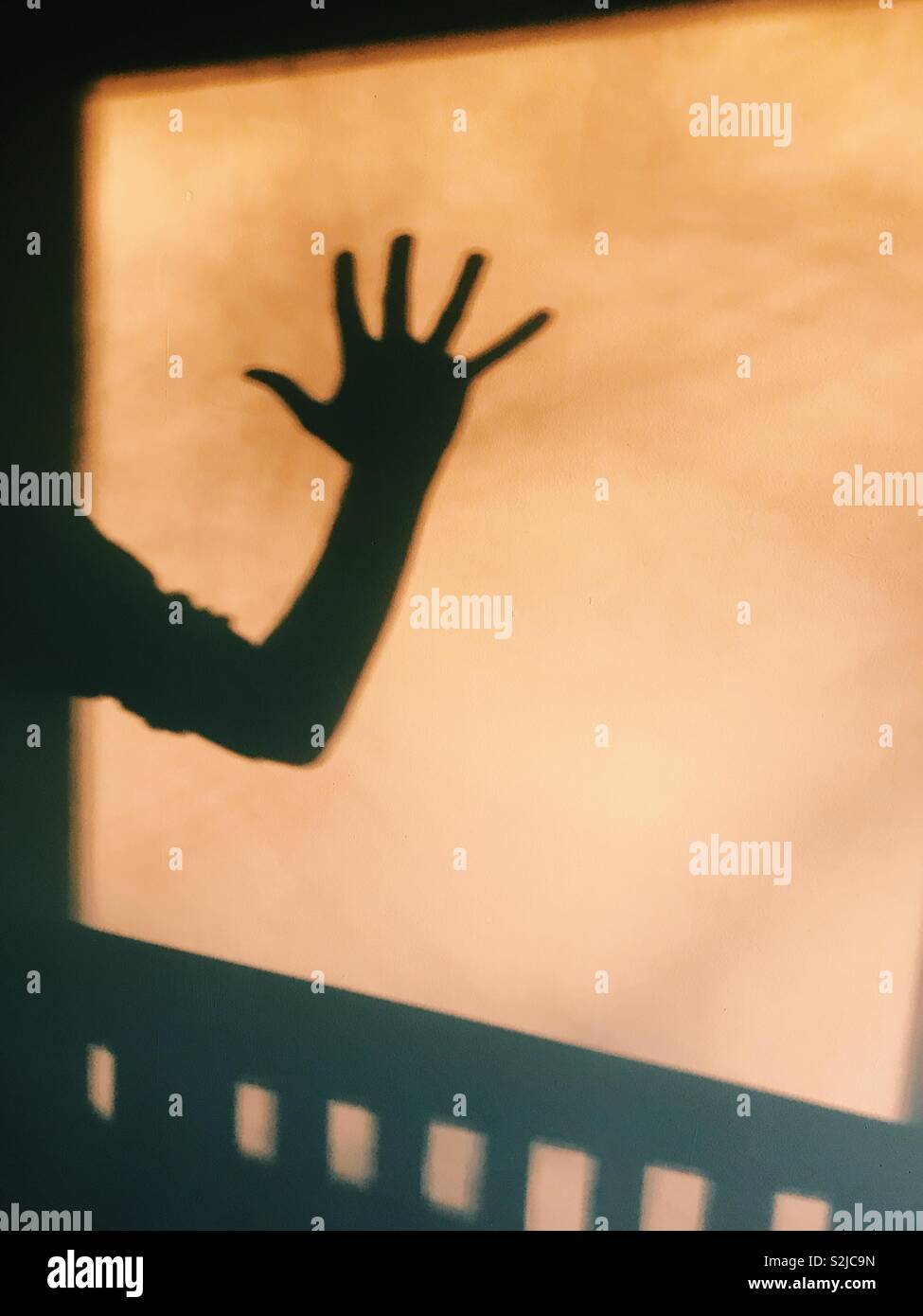 Shadow of a man’s arm and hand waving. Stock Photo