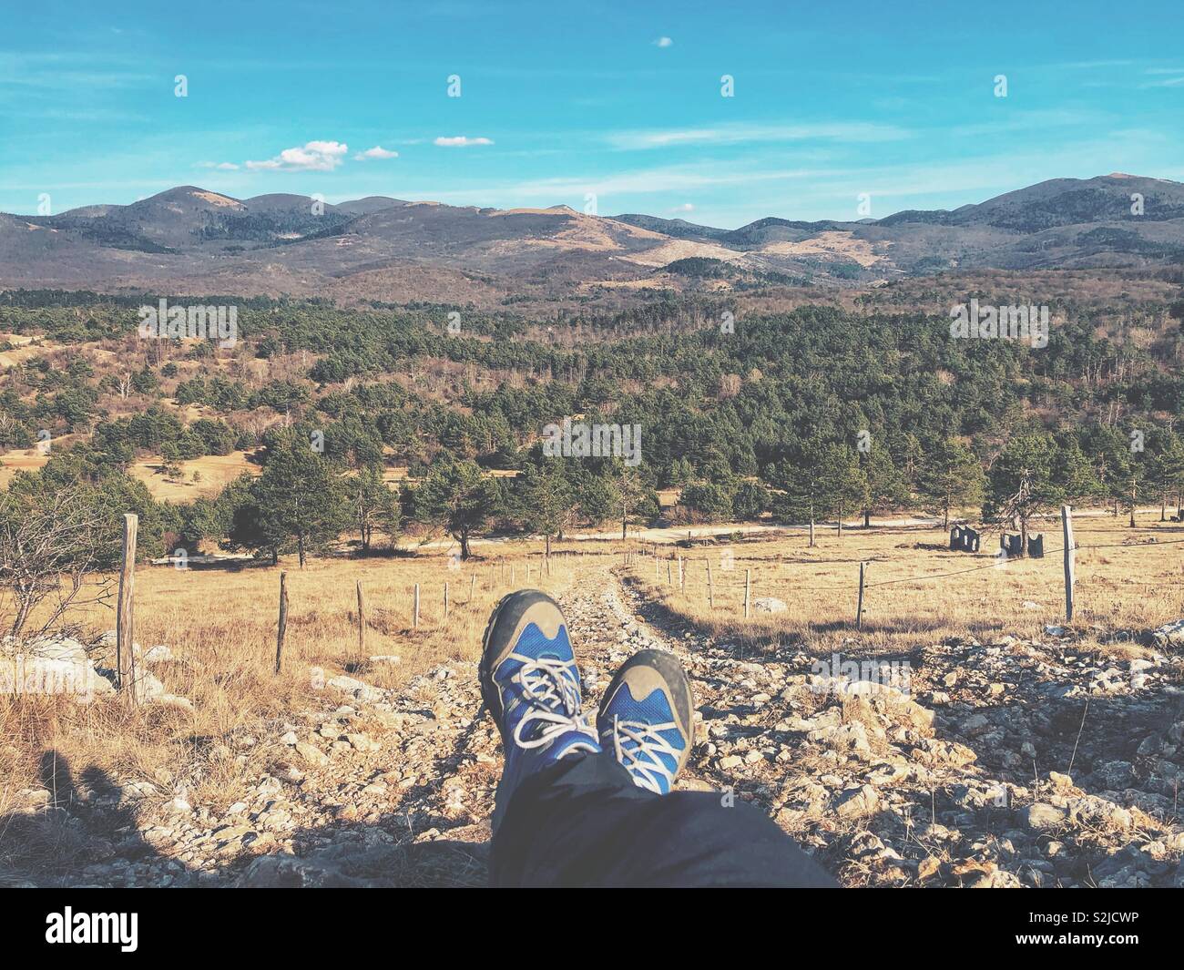 Hiker resting on a hill enjoying the view. Feet only with trail running shoes on. - Smartphone Captured Stock Image
