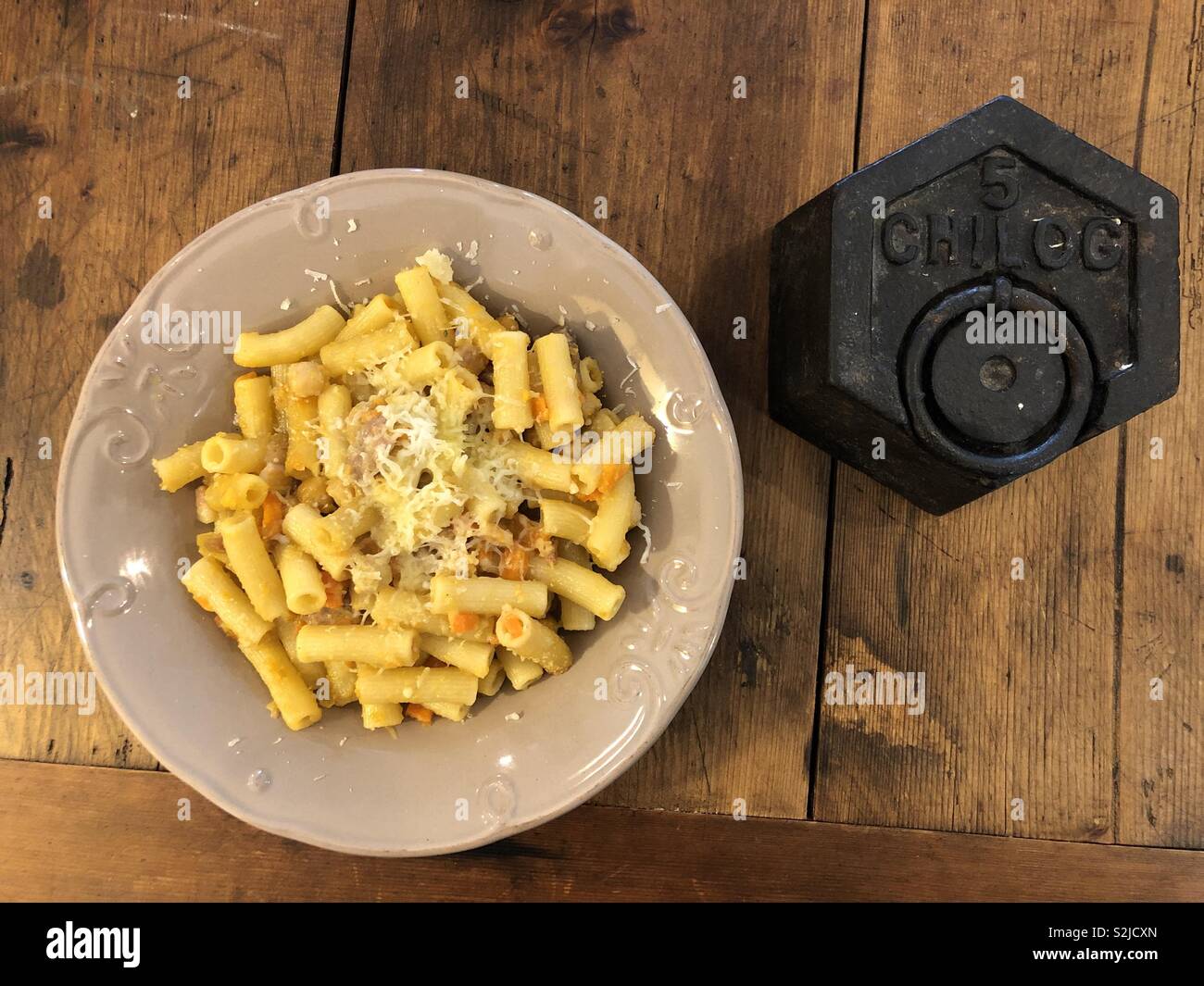 Organic noodles dish with a steelyard balance weight on a wooden table - Smartphone Captured Stock Image