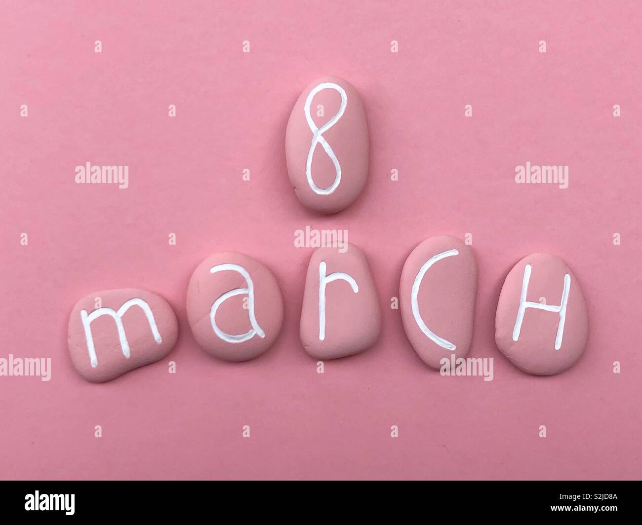 8 March, Women’sDay celebrated with pink colored stones over pink background Stock Photo