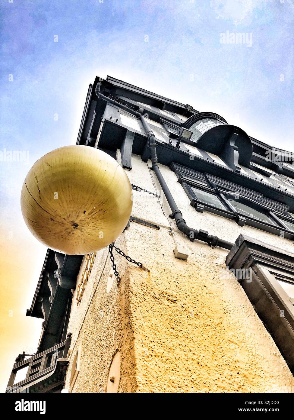 View from below of an advertising golden ball hanging outside a pub Stock Photo