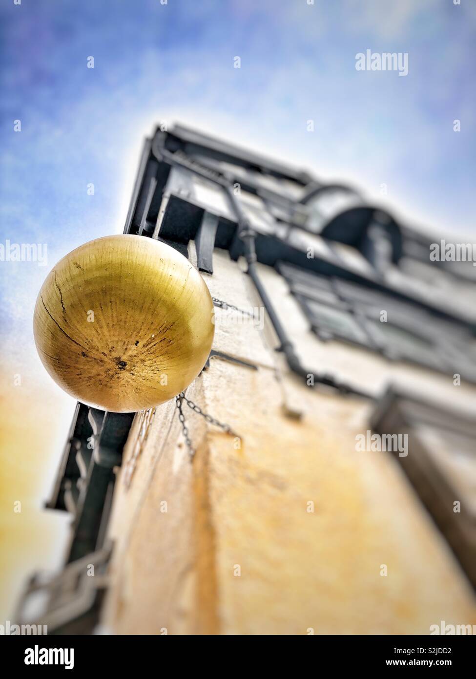 Focus on a golden ball advertising feature hanging outside a pub in Scarborough, UK. Viewed from below. Lens blur. - Smartphone Captured Stock Image