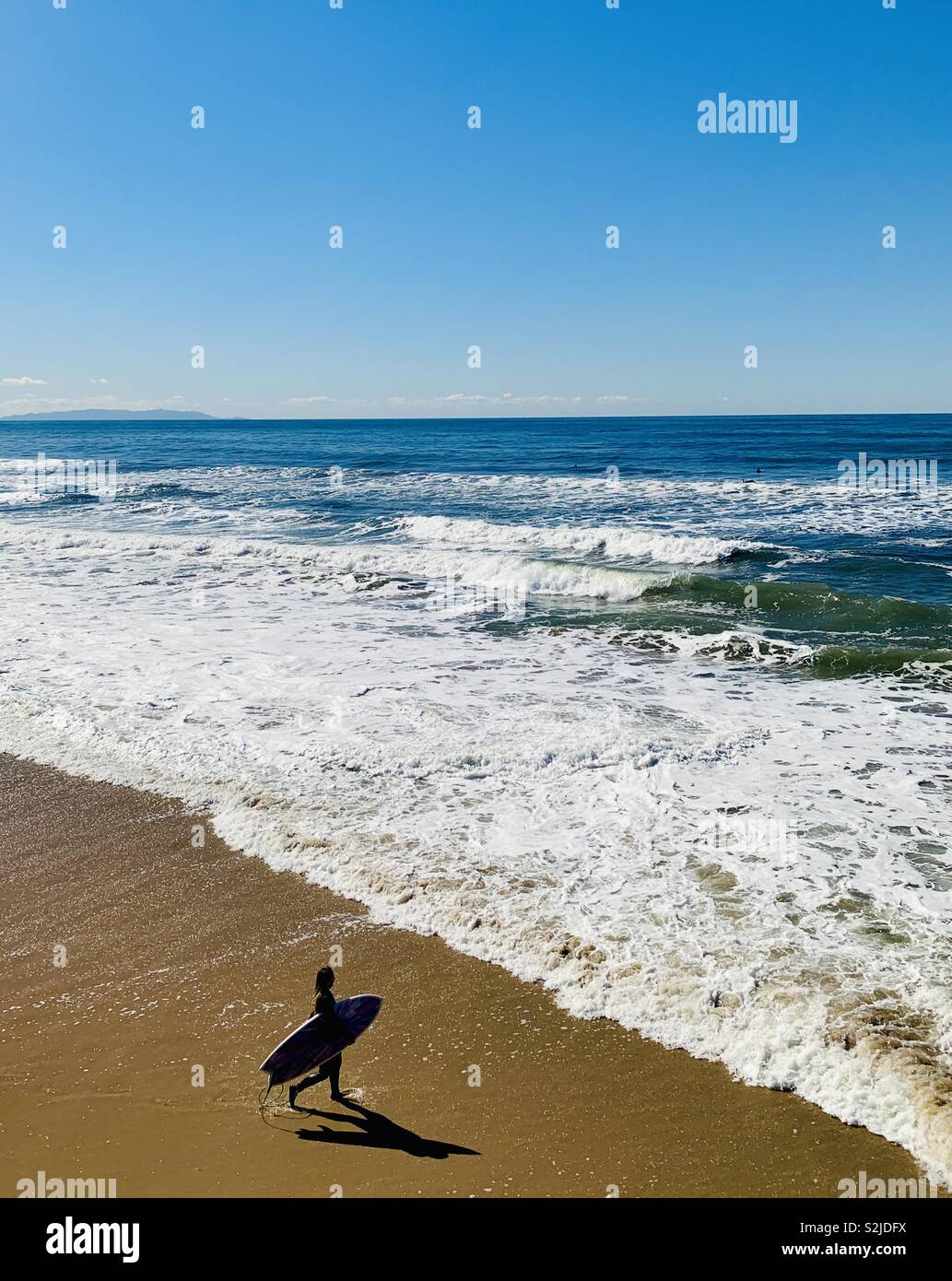 Female surf walking out to surf. Manhattan Beach, California USA. Stock Photo