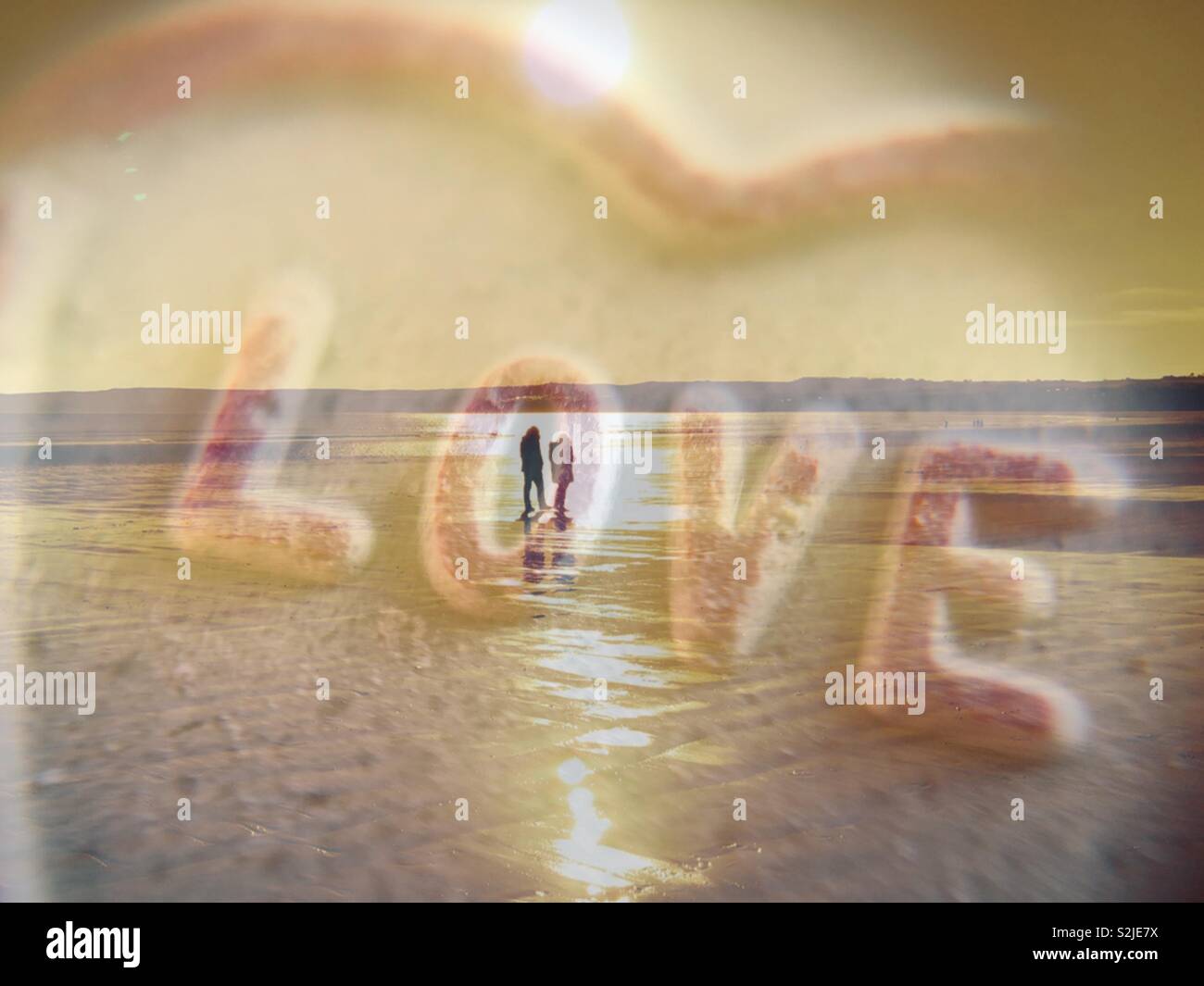Double exposure of a couple walking along a beach and the word love - Smartphone Captured Stock Image