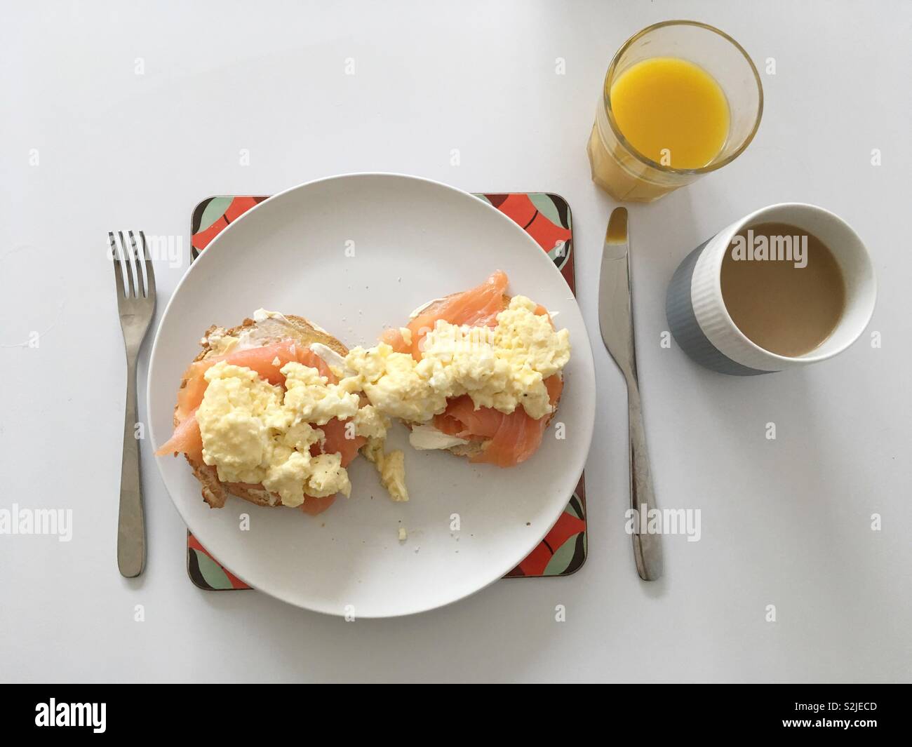 Smoked salmon and scrambled eggs on a bagel, with a glass of orange juice and coffee in Royal Copenhagen cup - Smartphone Captured Stock Image