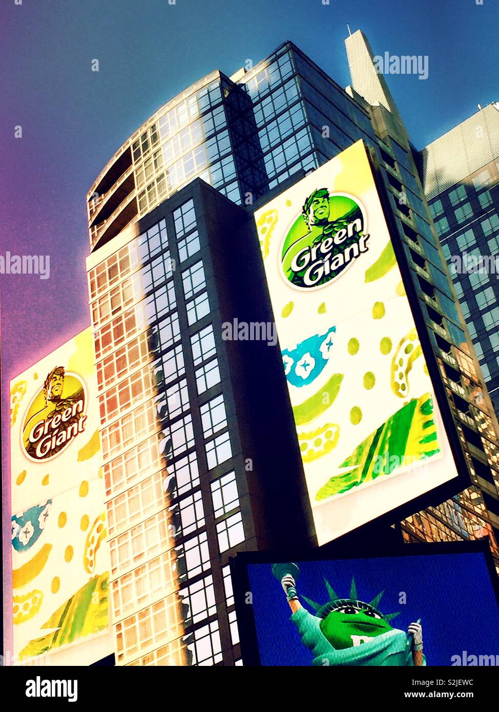 Huge electronic billboard featuring green giant vegetables above the M&M candy store in Times Square, New York City, USA - Smartphone Captured Stock Image