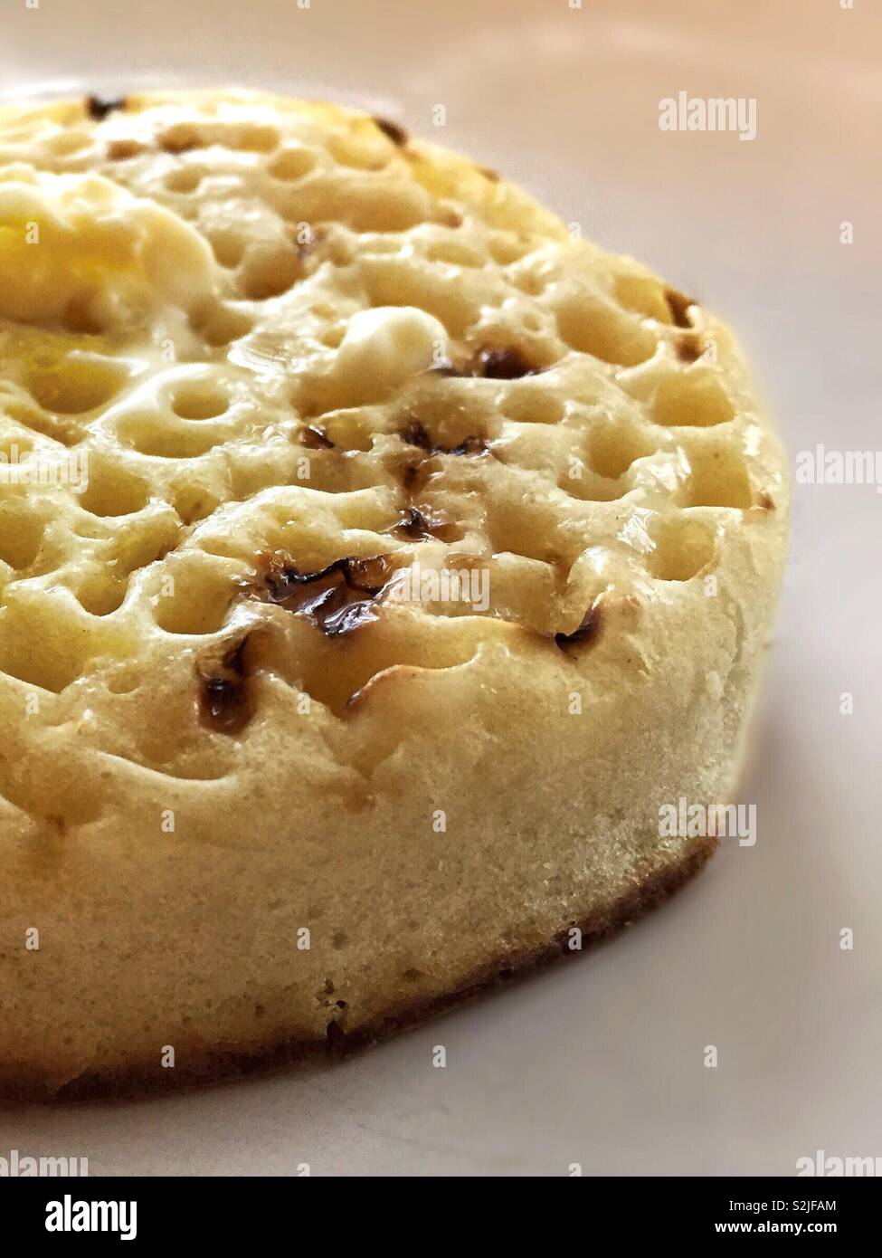 Crumpet for breakfast nice and hot and buttery.  Perfect filling start to the day toasted or grilled.  Crisp and soft pillowy bread based food Stock Photo