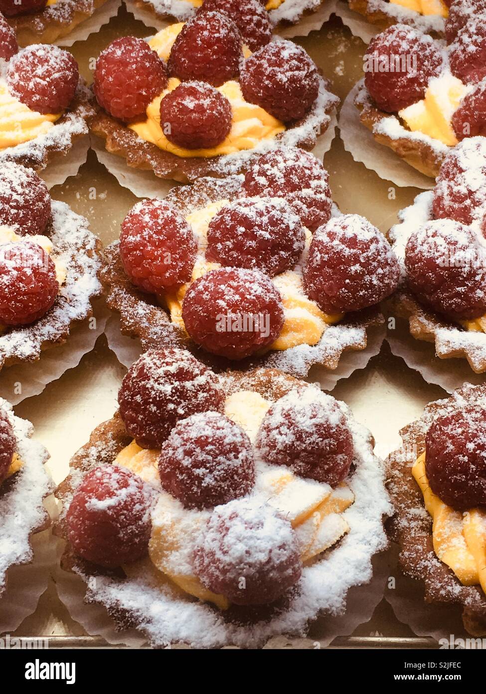 Professionally prepared mouth watering delicious raspberry tarts with an orange cream and powdered sugar. - Smartphone Captured Stock Image