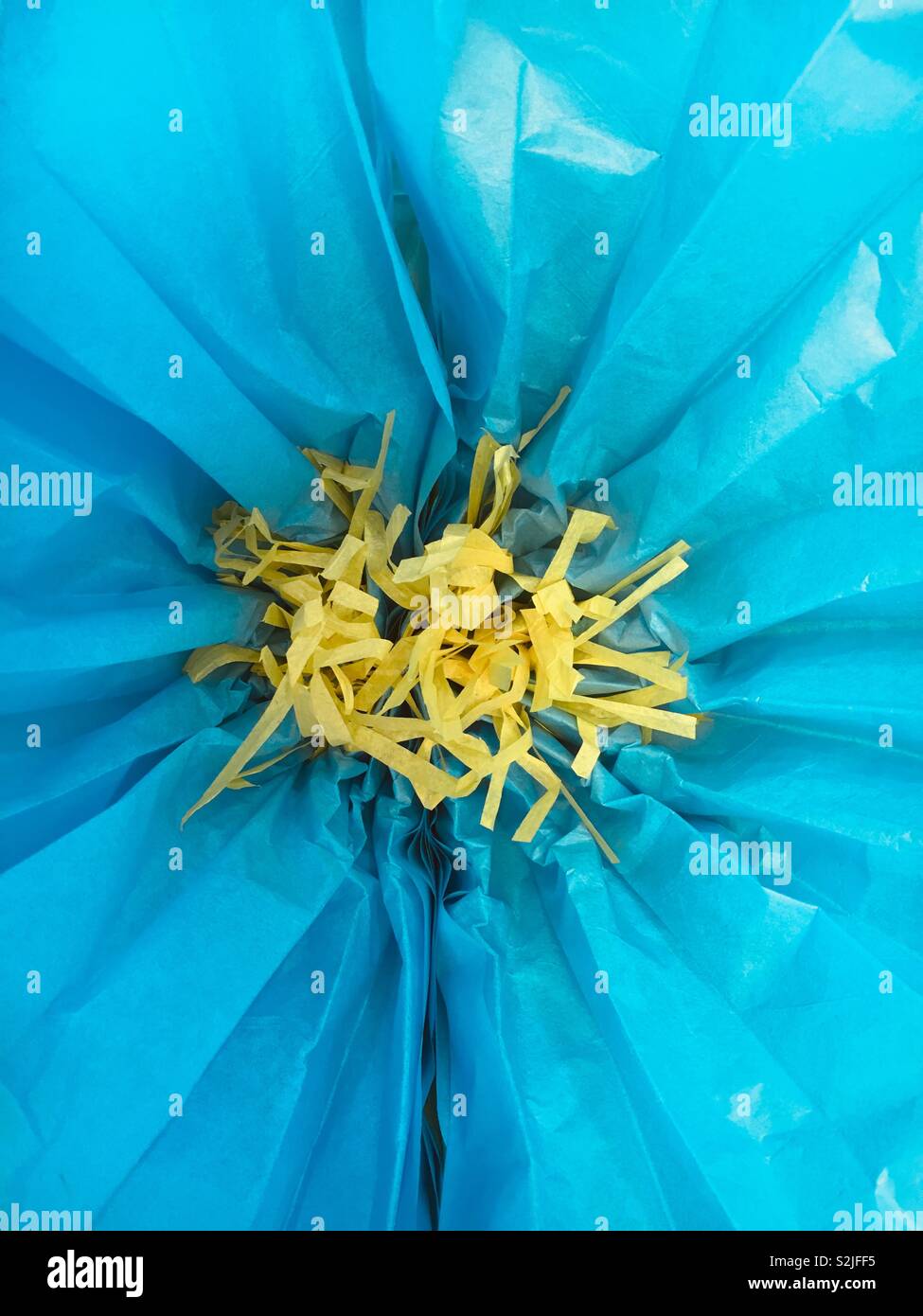 Beautiful bright blue and yellow spring flower made out of crepe paper used as a table setting. - Smartphone Captured Stock Image