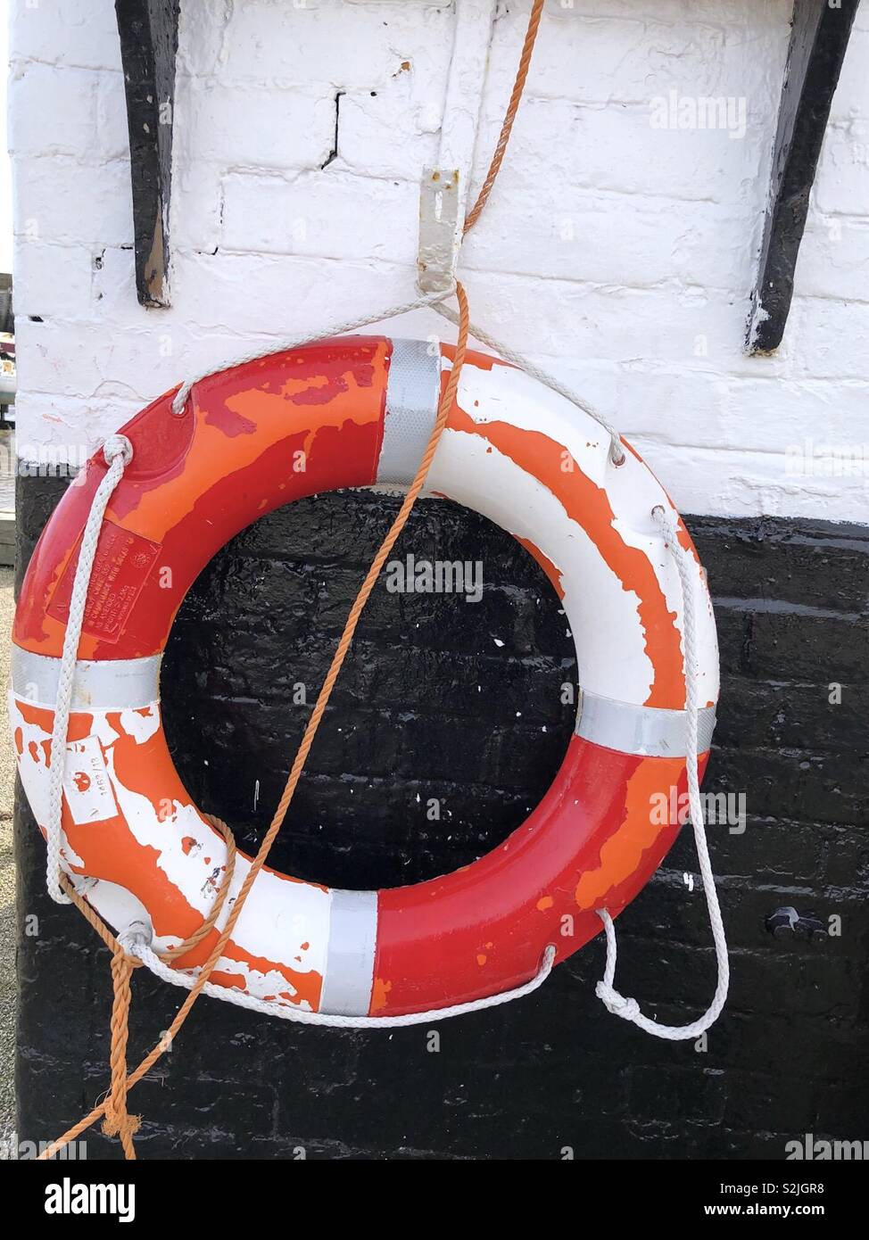 Paint peeling off a red and white life preserver with throwline - Smartphone Captured Stock Image