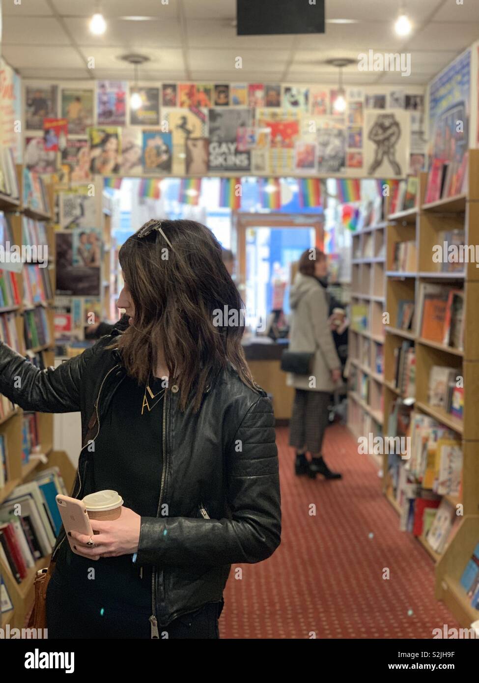 Two women browse and shop for books in a bookstore - Smartphone Captured Stock Image
