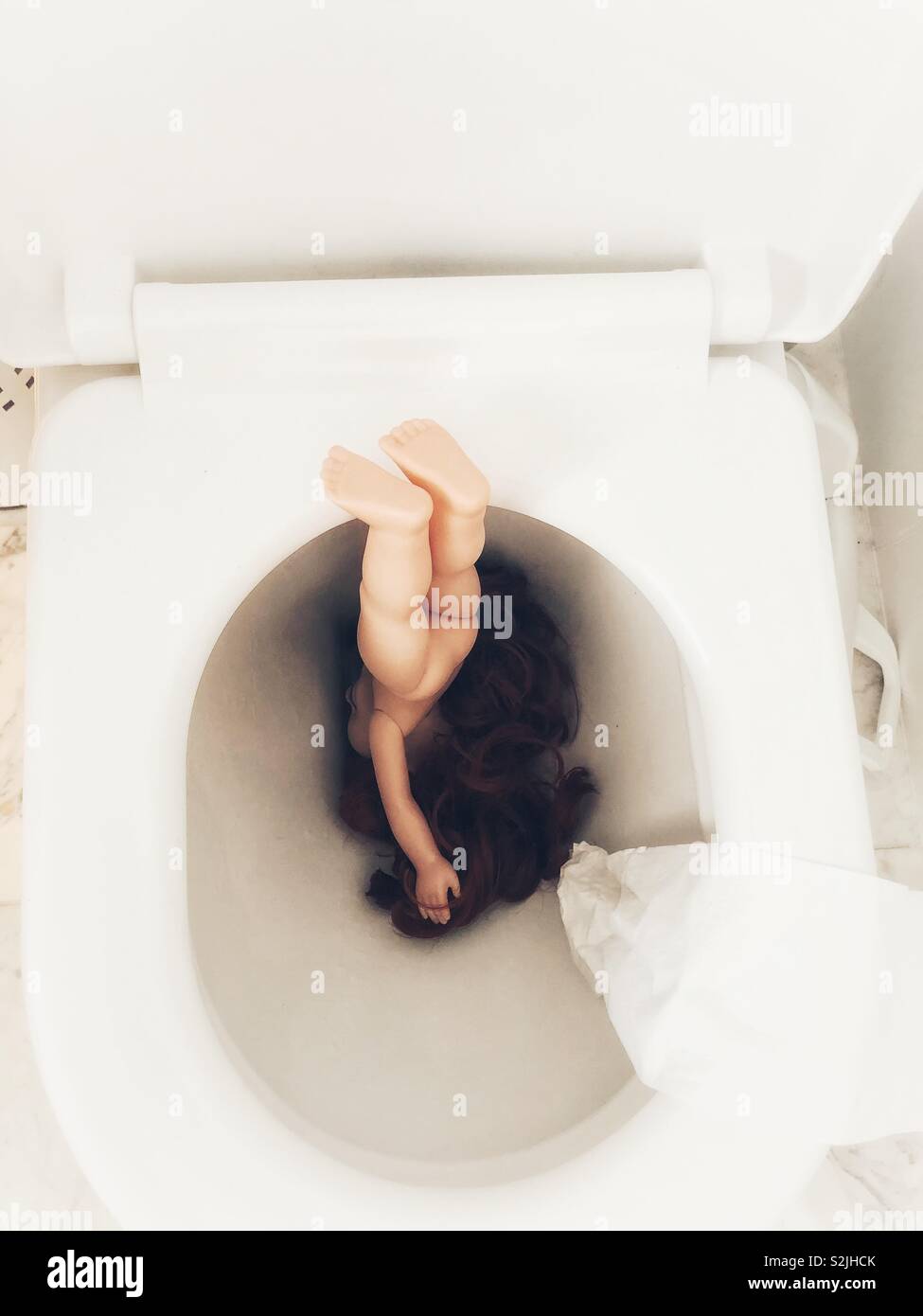 Doll flushed down a toilet Stock Photo